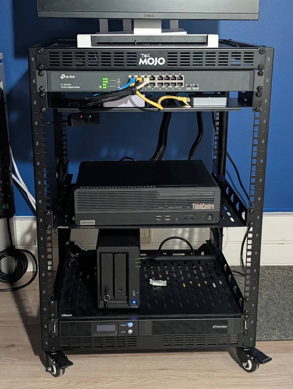 The open-frame 16U rack: a TP-Link 16-port switch at the top, the Lenovo ThinkCentre on the middle shelf, the Synology DS723+ NAS on the lower shelf and the PowerWalker UPS at the bottom